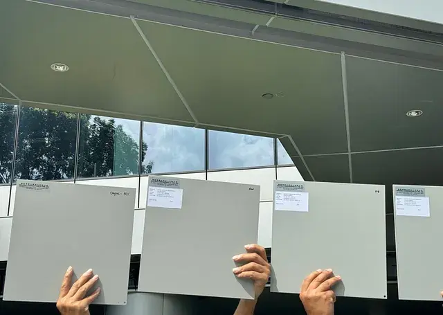 Aluminium coating panels held outdoors to compare colour and sheen in sunlight