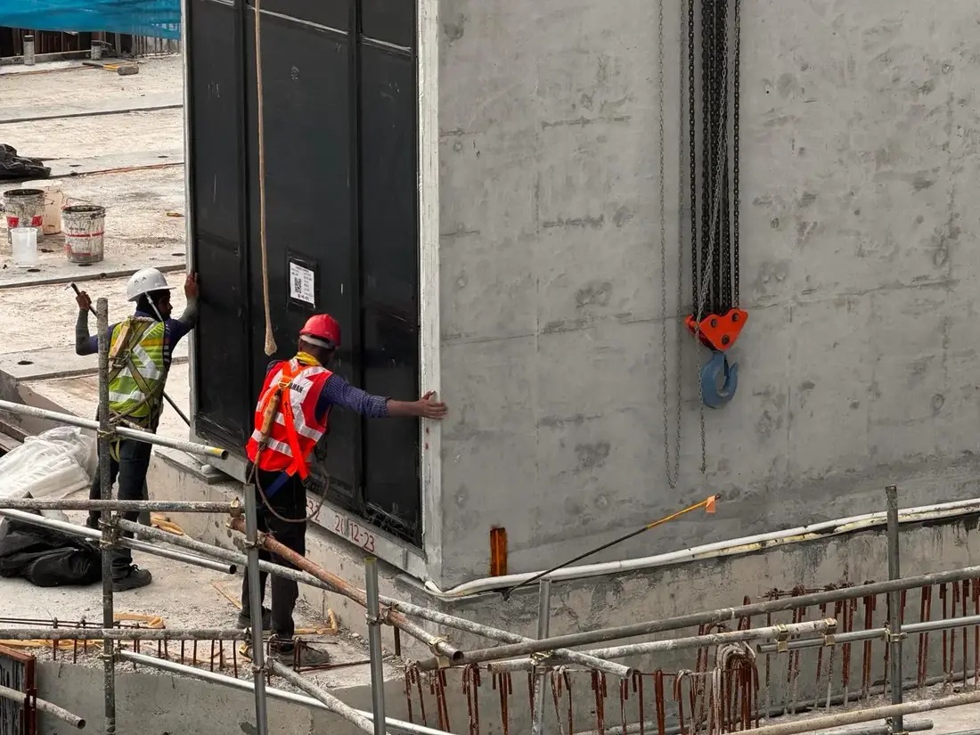 Construction workers guiding a prefabricated PPVC module into position on site