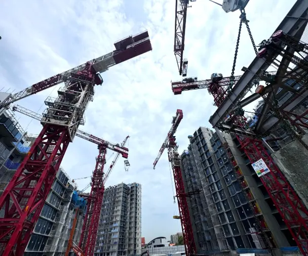 Topless tower cranes lifting PPVC modules during the initial installation levels