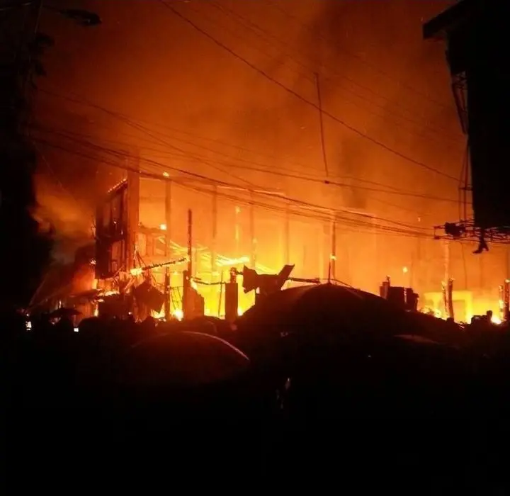 A row of wooden shophouses engulfed in fire at night