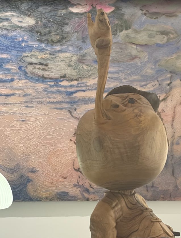 Long-nosed wooden character beneath a painted ceiling