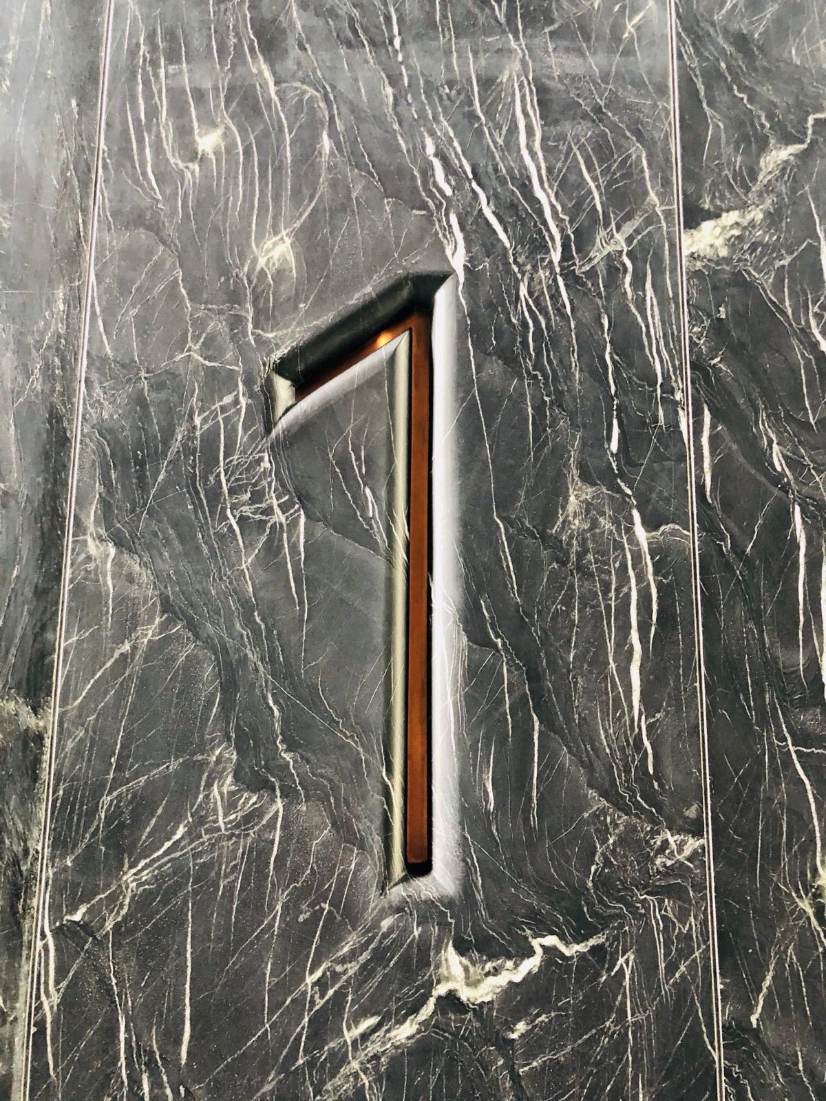 Level marker precisely integrated into dark Belvedere stone wall cladding